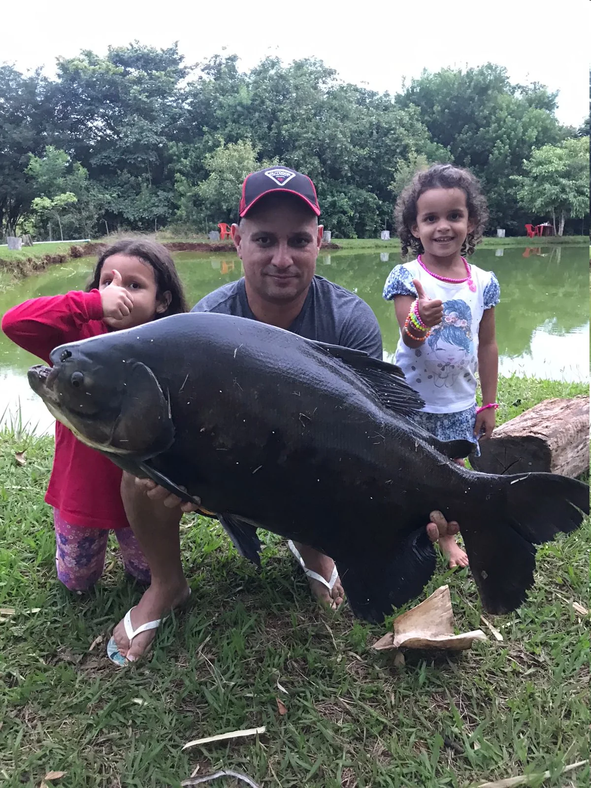 Família com crianças posando com um grande peixe