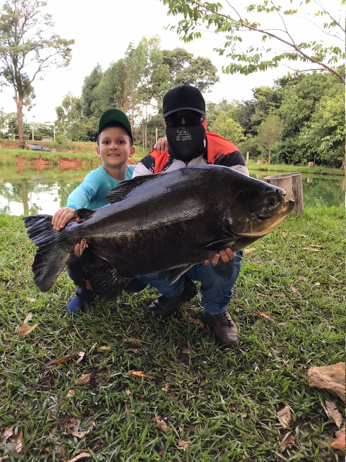 Pescador e criança segurando um grande peixe no Pesqueiro Vitória